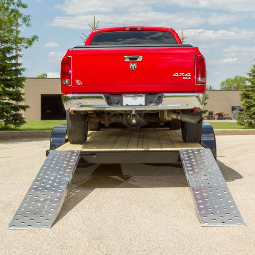 HD Ramps plate end car ramps successfully loading a pickup truck onto a flat trailer deck.