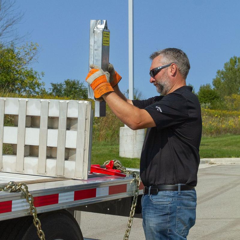A man installs the stake pocket supports onto the ramp component of the HD Ramps Master Kit (SKU: 23-20-192-02-02-MLL-2-KIT).