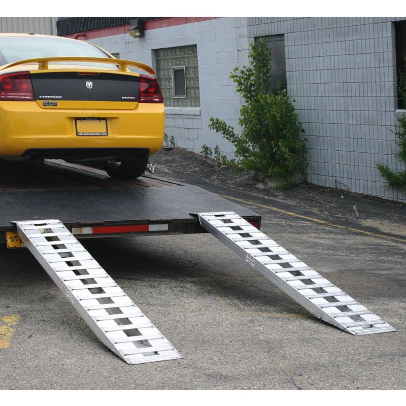 HD Ramps aluminum hook-end trailer ramps attached to a trailer bed supporting a loaded car.